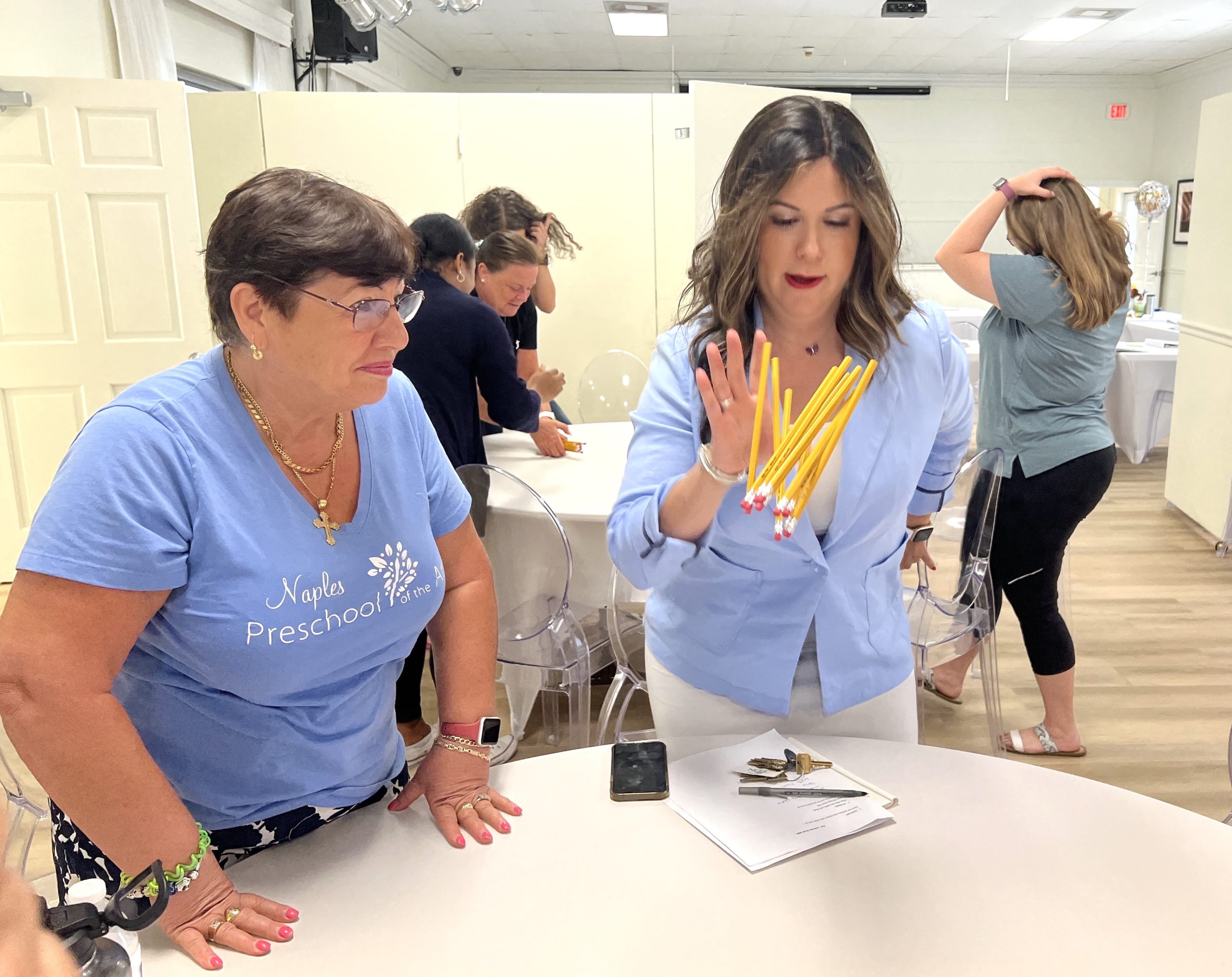 A group of women, in it to win it, standing around a table.
