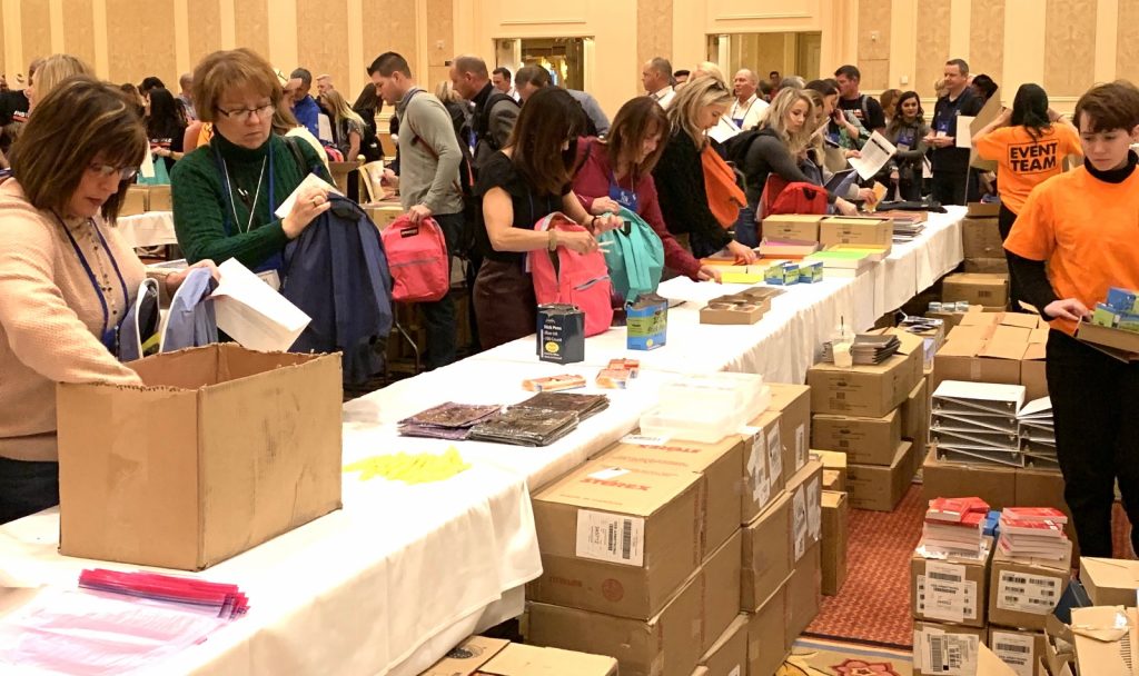 A group of people standing around a table full of care packs.