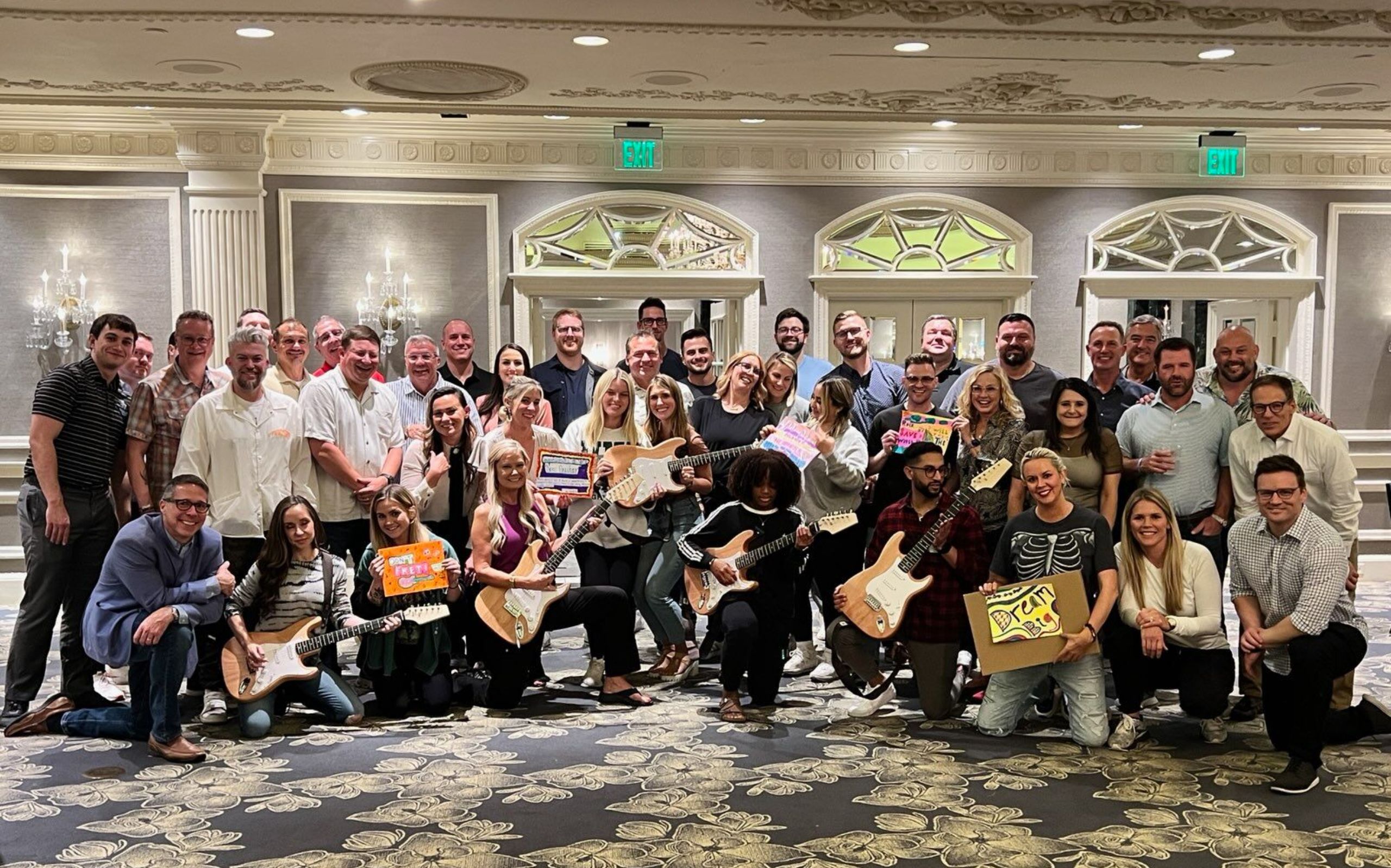 A group of people posing for a picture with guitars all over a room.