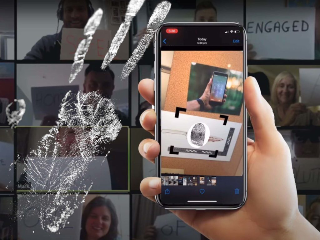 A hand holding a smartphone, displaying a magnifier app zooming in on a ring, surrounded by multiple obscured images of smiling people at a manor house.